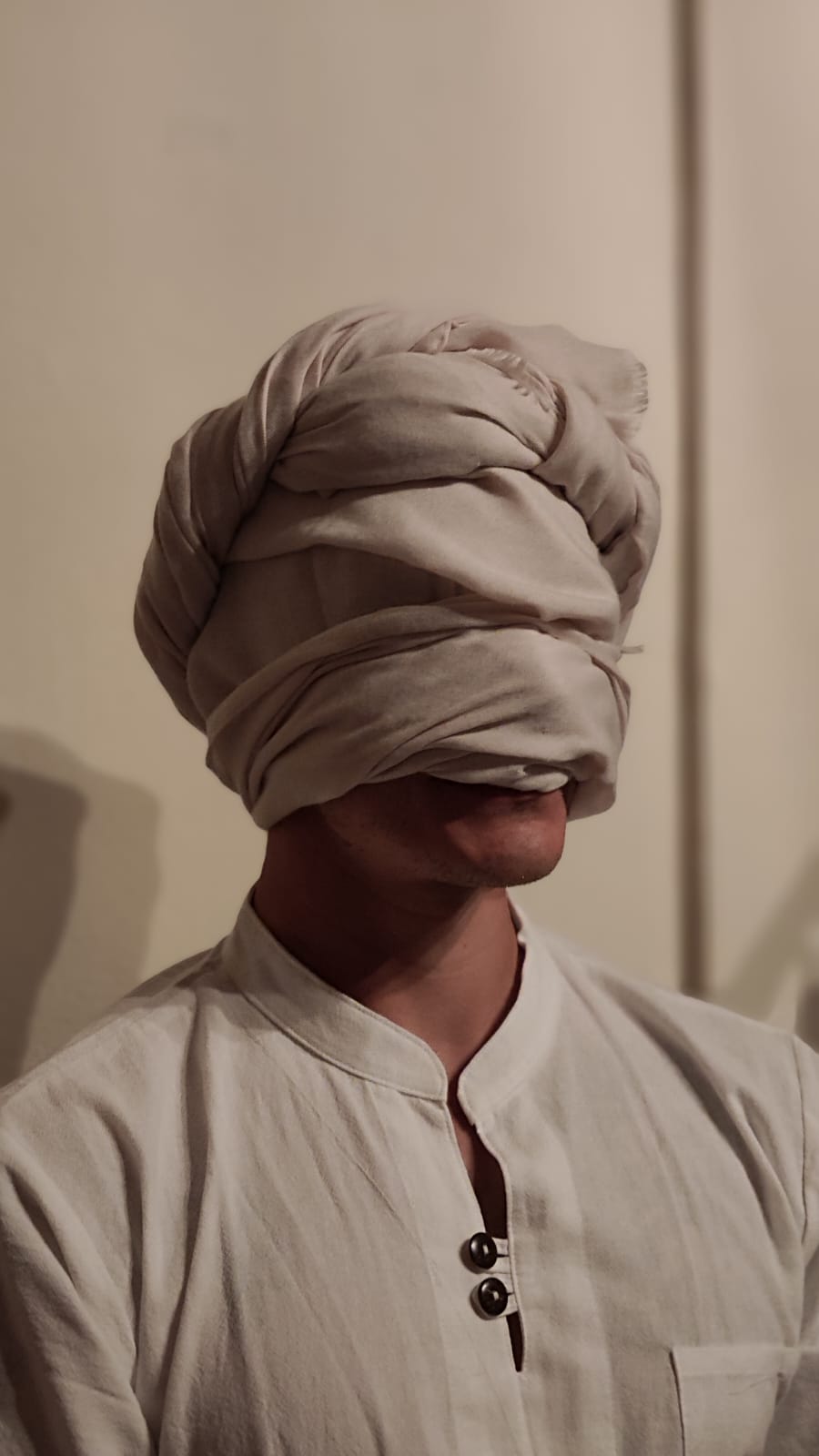 Adam Holman wearing white with his head wrapped in white cloth